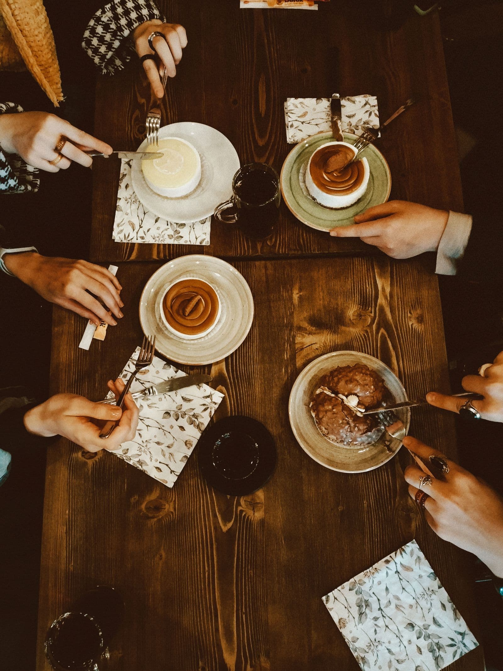 Four people sharing desserts and coffee at a café. Photo by Ayşe (Pexels)